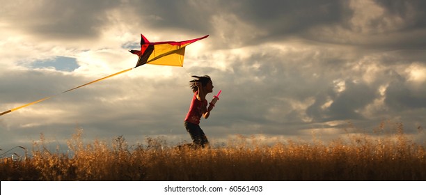 A panorama of a girl happily flying her kite. - Shutterstock ID 60561403