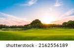 Panorama of golf course at sunset with beautiful sky. Scenic panoramic view of golf fairway. Golf field with pines