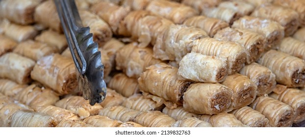 Panorama Of Greek Baklava Pastries At A Food Market With Tongs