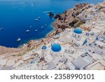 Panorama of Greek Orthodox Churc with blue dome and blue vibrant sea. Aerial view Santorini, Greece.