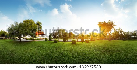 Panorama of a green garden with buddhist building and meadow with grass at early morning