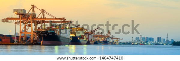 Panorama image of container cargo ship with ports\
crane bridge in harbor and refinery industrial at night logistics\
and transportation\
concept