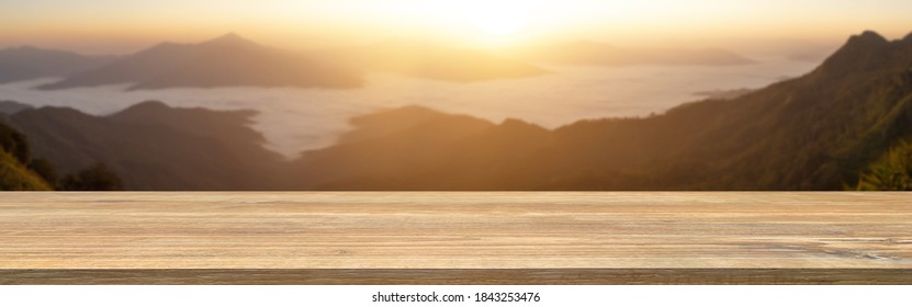 Panorama Image Of Wood Table In Blurry Foggy Landscape And Beautiful View Sunrise From Top Of The Mountain Background With Empty Space On The Table For Product Display And Counter Design Concept.