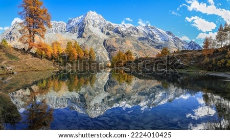 Panorama of Lac Bleu of Arolla lake in Canton Valais in colorful autumn season with reflection of Dent de Veisivi and Dent di Perroc peaks.