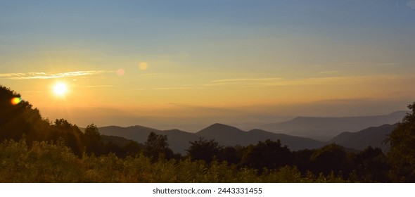 A panorama landscape picture of a sunset in the Shenandoah National Park, during golden hour with sunrays creating a lens flare; copy space, large size - Powered by Shutterstock