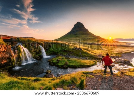 Panorama landscape of sunrise over volcanic Kirkjufell mountain with Kirkjufellsfoss waterfall and photographer man standing in summer at Snaefellsnes peninsula, Iceland