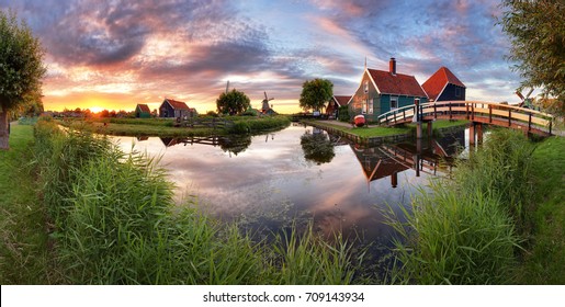 Panorama landscape windmills on water canal in village. Colorful spring sunset in Netherlands, Europe 