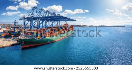 Panorama of a large container cargo ship beeing loaded and unloaded by large cranes in a commercial dock with copy space