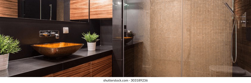 Panorama of luxurious dark bathroom interior with shower