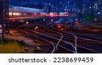 Panorama at main station of Hagen in Westphalia Germany at blue hour twilight. Railway tracks with switches, lamp lights and blurred trains in motion. Colorful railway infrastructure and technology. 