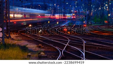 Panorama at main station of Hagen in Westphalia Germany at blue hour twilight. Railway tracks with switches, lamp lights and blurred trains in motion. Colorful railway infrastructure and technology. 