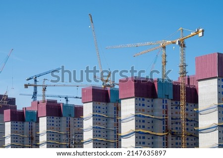 Panorama with many construction tower cranes in clear blue sky.