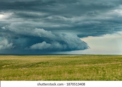 Panorama of a massive mesocyclone weather supercell, which is a pre-tornado stage, passes over a grassy part of the Great Plains while fiercely trying to form a tornado.