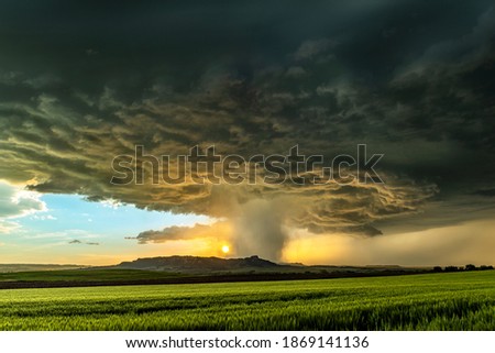Panorama of a massive mesocyclone weather supercell, which is a pre-tornado stage, passes over a grassy part of the Great Plains while fiercely trying to form a tornado.


