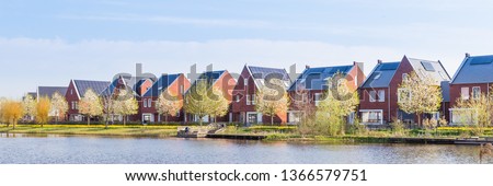 Panorama with modern brick houses along water in a family friendly suburban neighborhood in Veenendaal in the Netherlands.