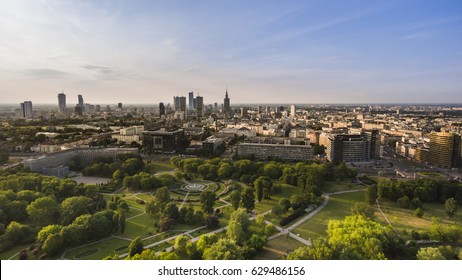 Panorama Of A Modern European City. Skyline Of Warsaw, Capitol Of Poland. Green Park And Trees In Foreground, Urban City In Background. Sunny Weather.