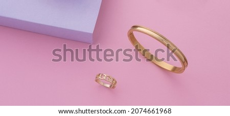 Panorama of Modern gold bracelet and ring on pastel colors background with copy space