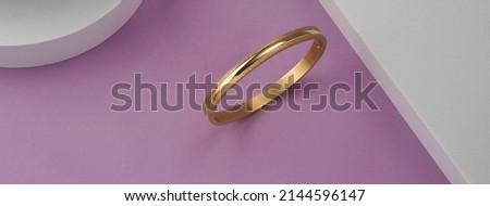 Panorama of modern golden bracelet on pink and white background with copy space