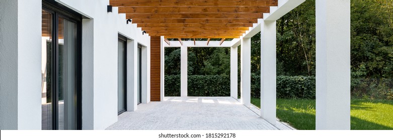 Panorama of modern house veranda with ceiling from wooden beams and cobblestone floor and green garden - Shutterstock ID 1815292178