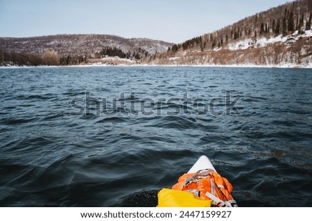 Panorama of a mountain river, rafting on a board with a paddle, things lying on the bow of the boat, spring in the mountains, a lake at a height. High quality photo