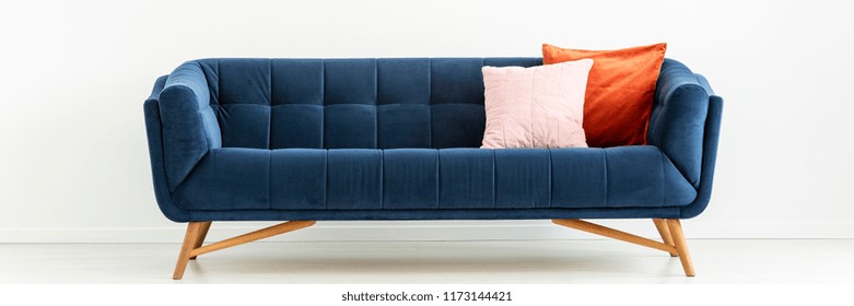 Panorama of navy blue settee with colorful cushions in white living room interior. Real photo