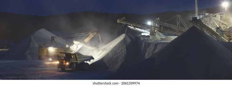 Panorama of night work at a mining and processing plant, loading and transportation of crushed stone.