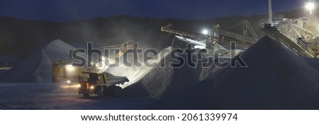 Panorama of night work at a mining and processing plant, loading and transportation of crushed stone.