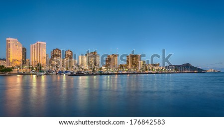 Panorama of the nightime skyline of Honolulu and Waikiki from Ala Moana park as the sun sets and illuminates the facades of the hotels and apartments