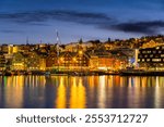 Panorama of the Norwegian city of Tromso on a winter evening during the Christmas season. The boat dock and downtown are illuminated by city lights.