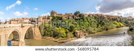 Panorama of the old historical city of Toledo with the bridge Puente de San Martín on the left and the river Rio Tajo in front. Toledo, Spain