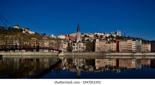 Panorama of old lyon in France with in the foreground the river Saône with the church Saint George, the basilica Notre Dame de fourvière on the heights and the footbridge at sunrise.