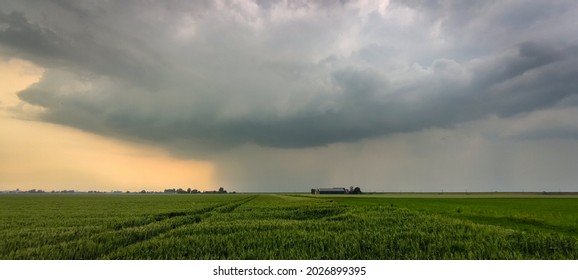 Panorama of an ominous looking thunderstorm with distinct updraft and downdraft over the fields at sunset