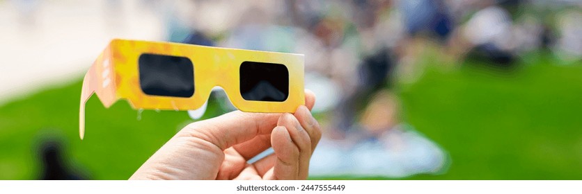 Panorama paper optics solar eclipse glasses scratch resistant polymer lenses filter harmful ultraviolet, infrared ray, blurry crow people on grassy yard watching totality show in Dallas, Texas. USA