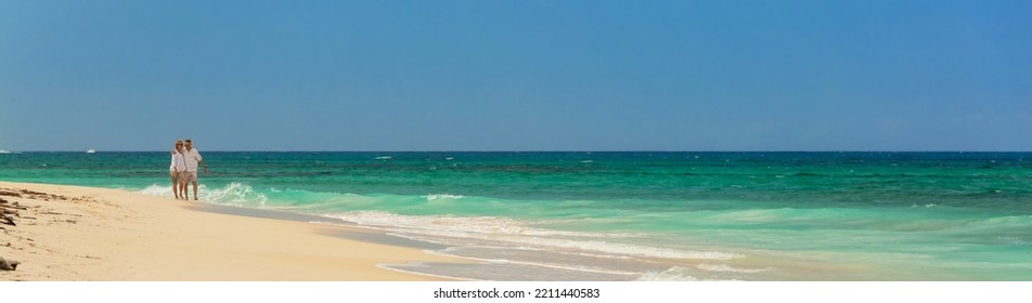 Panorama Of Paradise Island With Senior Caucasian Couple Walking By Turquoise Ocean On Romantic Tropical Vacation Bahamas