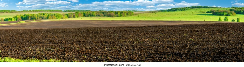 Panorama photo rows of soil before planting. Furrows row pattern in a plowed field prepared for planting crops in spring. Panorama view - Shutterstock ID 2155567703