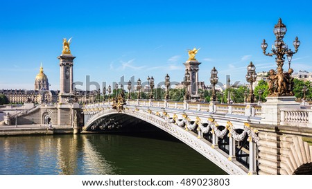 Panorama of Pont Alexandre III bridge over river Seine and Hotel des Invalides in the summer morning. Bridge decorated with ornate Art Nouveau lamps and sculptures. Paris, France