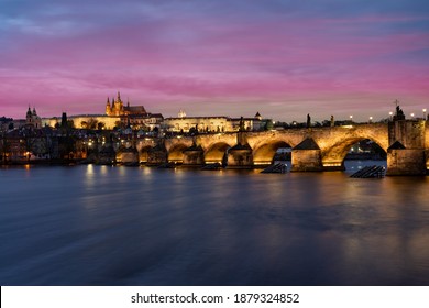 panorama prague castle and charles bridge and st. vita church lights from street lights are reflected on the surface of the vltava river in the center of prague at night in the czech republic