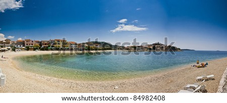 Panorama of Primosten beach and town - Pebble beach with an easychair and view to Primosten
