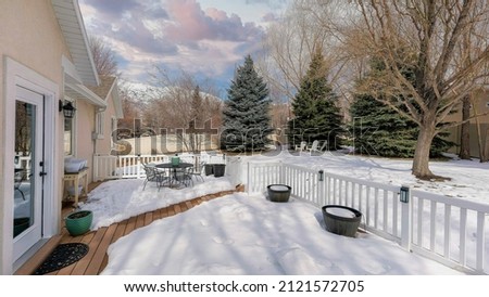 Panorama Puffy clouds at sunset Snow covered deck of a house with white railing and wood planks