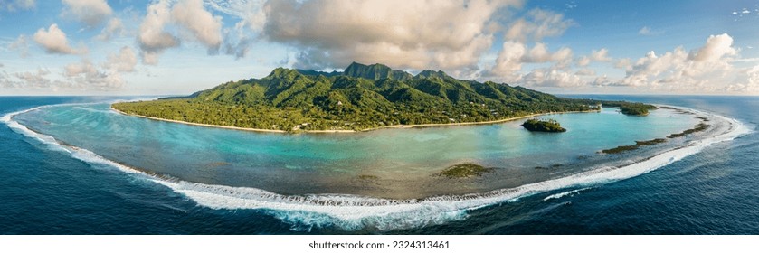 Panorama of Rarotonga, Cook Islands with the Muri Lagoon in the foreground and tropical mountains in the background at surnrise with waves breaking over the reefs