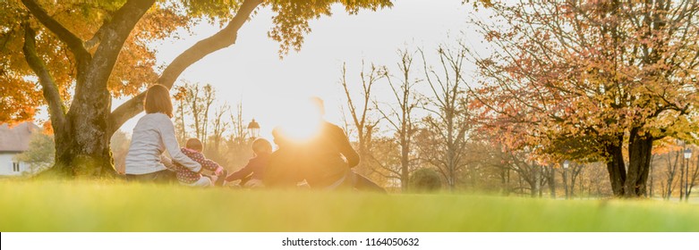 Panorama Rear View Of Young Family With Three Kids Enjoying A Day Together Backlit By A Beautiful Evening Sun.