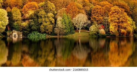 Panorama of the reflection of the autumn foliage of the forest in the water. Autumn forest river reflection. Autumn forest reflected in river water. Autumn river reflection