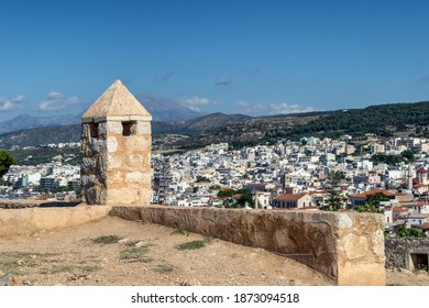 Panorama of Rethymno city (Crete, Greece) view from the mountain from the ancient fortress of Fortezza. Summer sunny day, blue sky, yellow walls and towers of the fortress. Many houses on the mountain - Shutterstock ID 1873094518