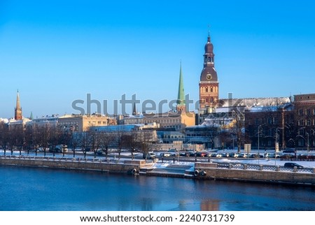 Panorama of Riga, the capital of Latvia, by the river Daugava on a clear, sunny winter day. View from the Stone Bridge. Dom Church, Anglican Church. Blue sky in the background.