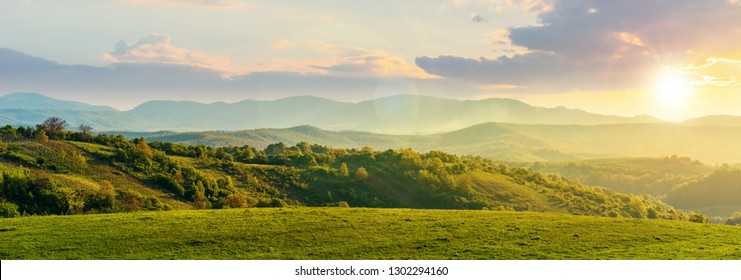 panorama romania countryside at sunset in evening light  wonderful springtime landscape in mountains  grassy field   rolling hills  rural scenery