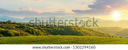 panorama of romania countryside at sunset in evening light. wonderful springtime landscape in mountains. grassy field and rolling hills. rural scenery