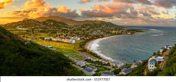 Panorama of Saint Kitts and its capital Basseterre during sunset, beautiful green mountains and a beach in paradise caribbean island with amazing green and orange colors. Saint kitts and nevis