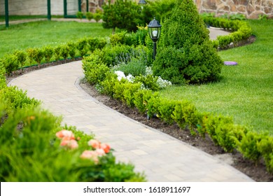 Panorama scenery of park, green lawn, grass, bushes, and pathwalk. Brick wall of house and garden lantern. Ready to use - Shutterstock ID 1618911697