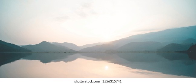 Panorama Scenic Of Mountain Lake With Perfect Reflection At Sunrise. Beautiful Mountain Range Landscape With Pink Pastel Sky With Hills On Background And Reflected In Water. Nature Lake Landscape