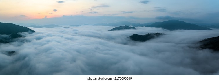 Panorama of sea of clouds around mountain peaks at sunrise - Shutterstock ID 2172093869